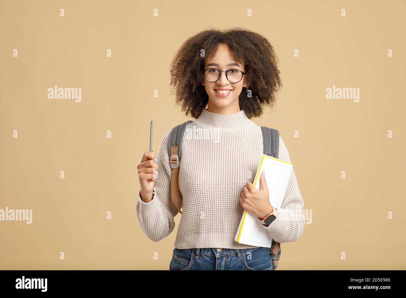 Joyeuse femme afro-américaine avec verres, chandail et bloc-notes lève le stylo, isolé sur fond jaune Banque D'Images