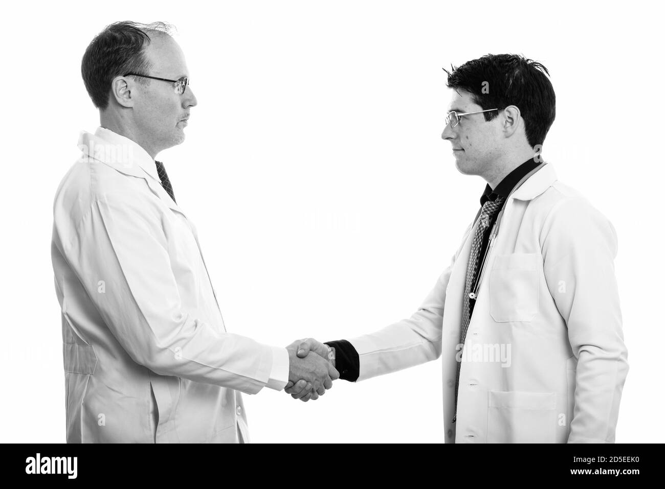 Vue de profil d'homme mûr et jeune homme médecin doctor shaking hands Banque D'Images