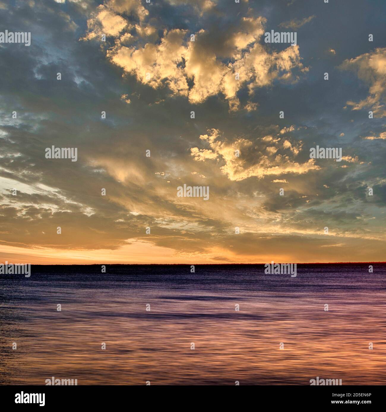 Magnifique coucher de soleil sur des eaux calmes avec des nuages spectaculaires et des couleurs vibrantes au crépuscule. Bretagne. France Banque D'Images