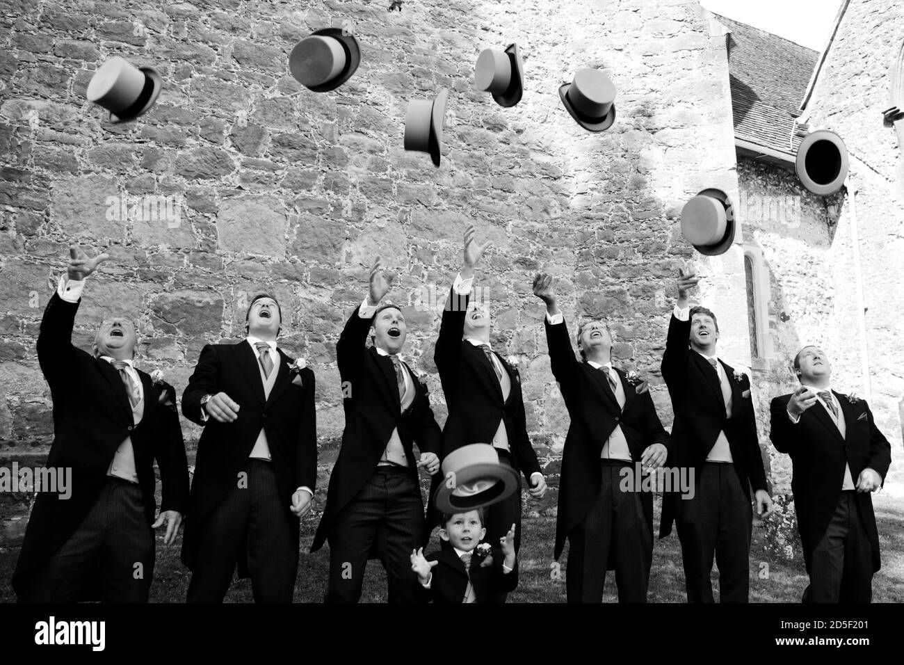 Les meilleurs chapeaux sont jetés dans l'air lors d'un mariage, avec un marié, des groommen et un garçon de page en costumes avec queues Banque D'Images