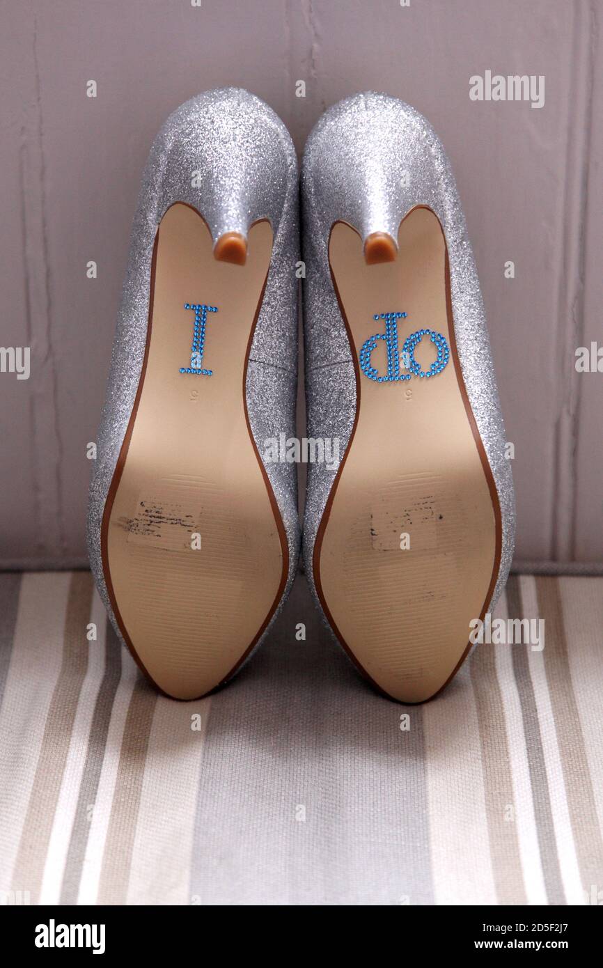 Un texte bleu « I do » est écrit au bas des chaussures de mariage étincelantes. Banque D'Images
