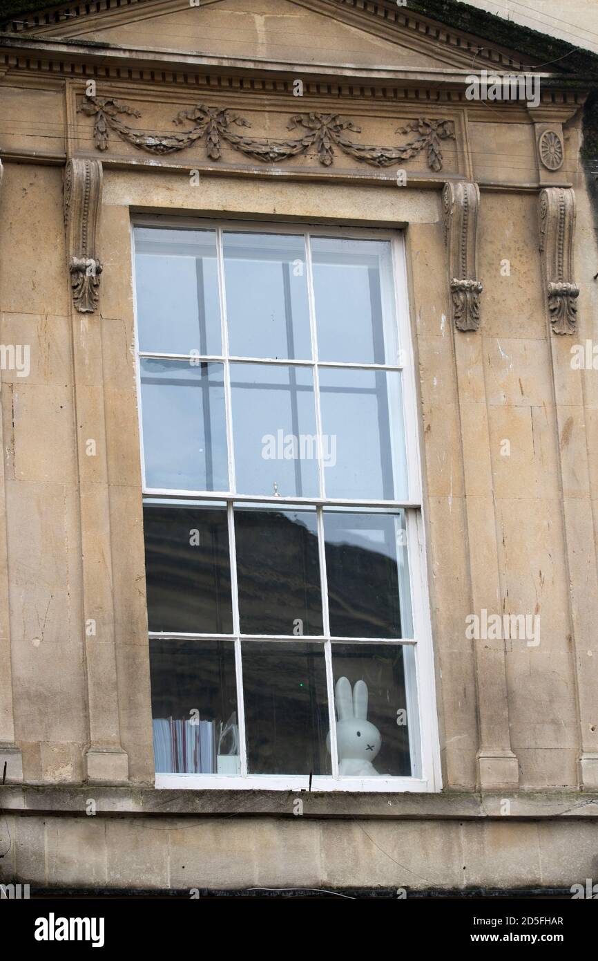 Un lapin en peluche donne sur une fenêtre géorgienne au-dessus des passants dans la ville de Bath, Somerset, Royaume-Uni Banque D'Images