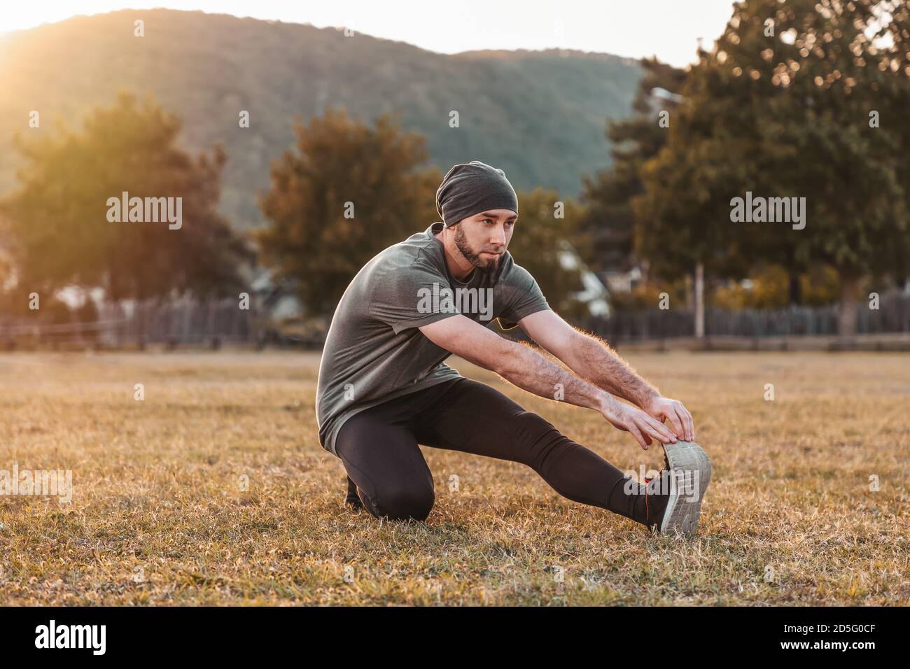 Sports et yoga. Un homme dans les vêtements de sport s'échauffe sur l'herbe avant l'entraînement. Teinte. Banque D'Images