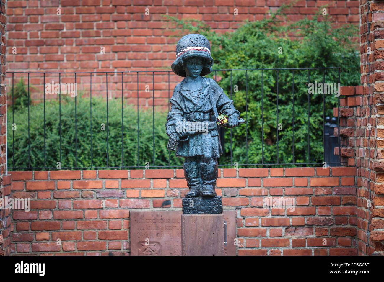 Monument de petit garçon insurgé dans un casque et des bottes allemands surdimensionnés, participant au soulèvement de Varsovie en 1944 contre la brique rouge des murs de la ville médiévale Banque D'Images