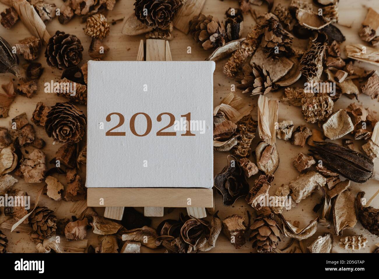2021 écrit en marron sur la toile d'un chevalet avec des fruits bruns séchés et des fleurs autour. Banque D'Images