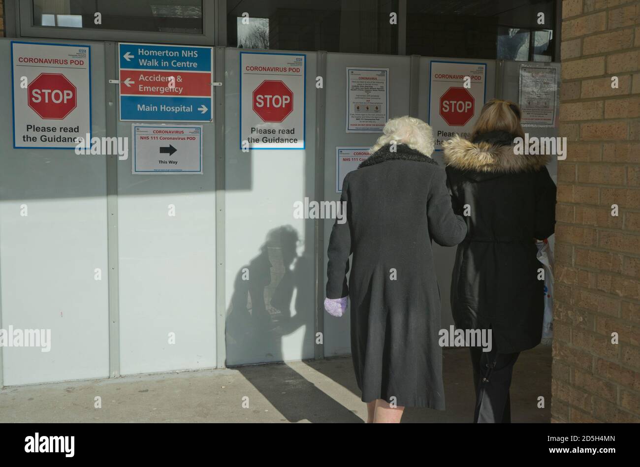 Les visiteurs âgés marchent à côté des signes vers la cosse du coronavirus à l'hôpital Homerton NHS de Londres, Angleterre, Royaume-Uni Banque D'Images