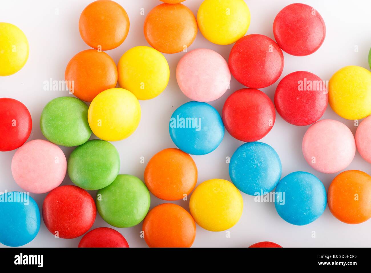 Dragées en chocolat multicolores colorées sur fond blanc. Vue de dessus, gros plan. Banque D'Images
