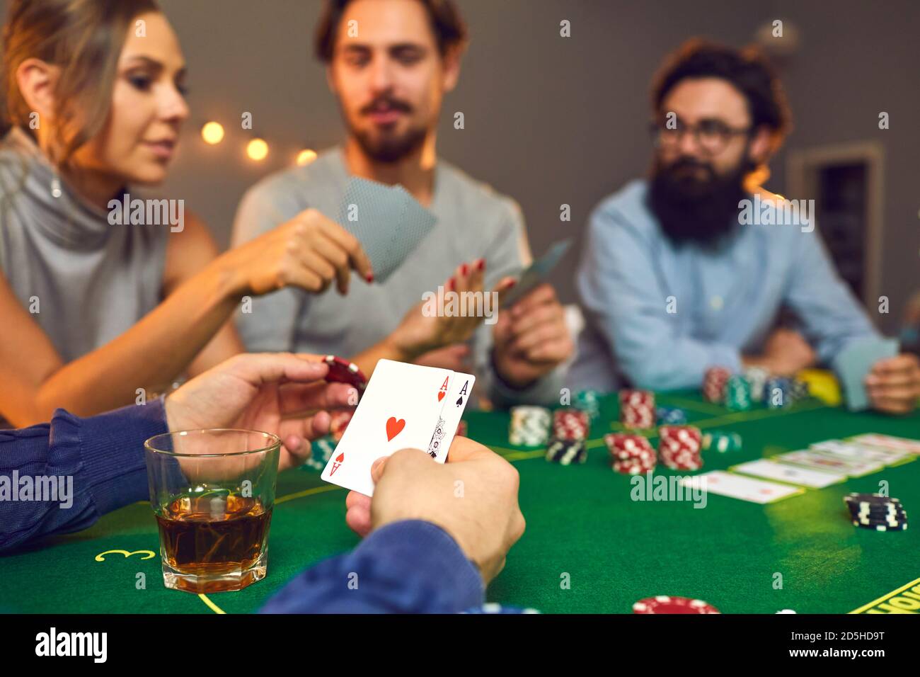 Homme tenant une puce et une paire d'as tout en jouant poker avec ses amis le soir du casino Banque D'Images