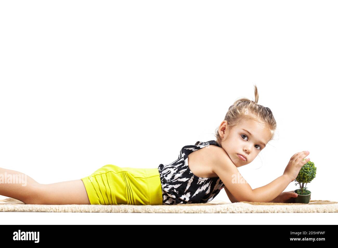 mignon litthe fille couché sur le sol et jouant avec petit petit arbre jouet Banque D'Images