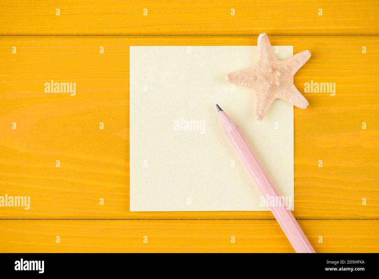Vue du dessus de la tête photo rognée d'un crayon vierge et l'étoile de mer isolée sur fond de bois jaune avec copyspace Banque D'Images