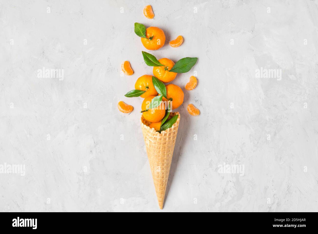 Mandarine ou orange mandarine dans un cône de glace gaufré avec des tranches de fruits sur fond de béton. Concept de la nourriture de Noël en hiver. Vue du dessus. flat Lay Banque D'Images