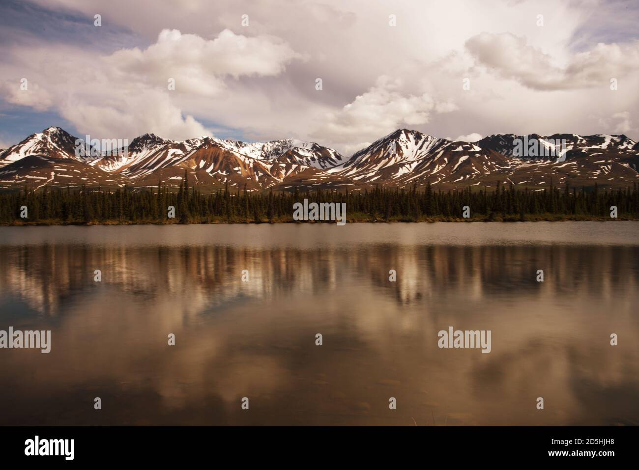 Sommets enneigés avec de la neige sur le sommet d'une rivière peu profonde au début de l'été. Banque D'Images