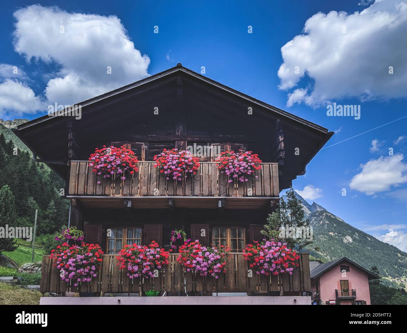 Belle maison de montagne en bois avec fleurs décoratives sur les balcons Banque D'Images