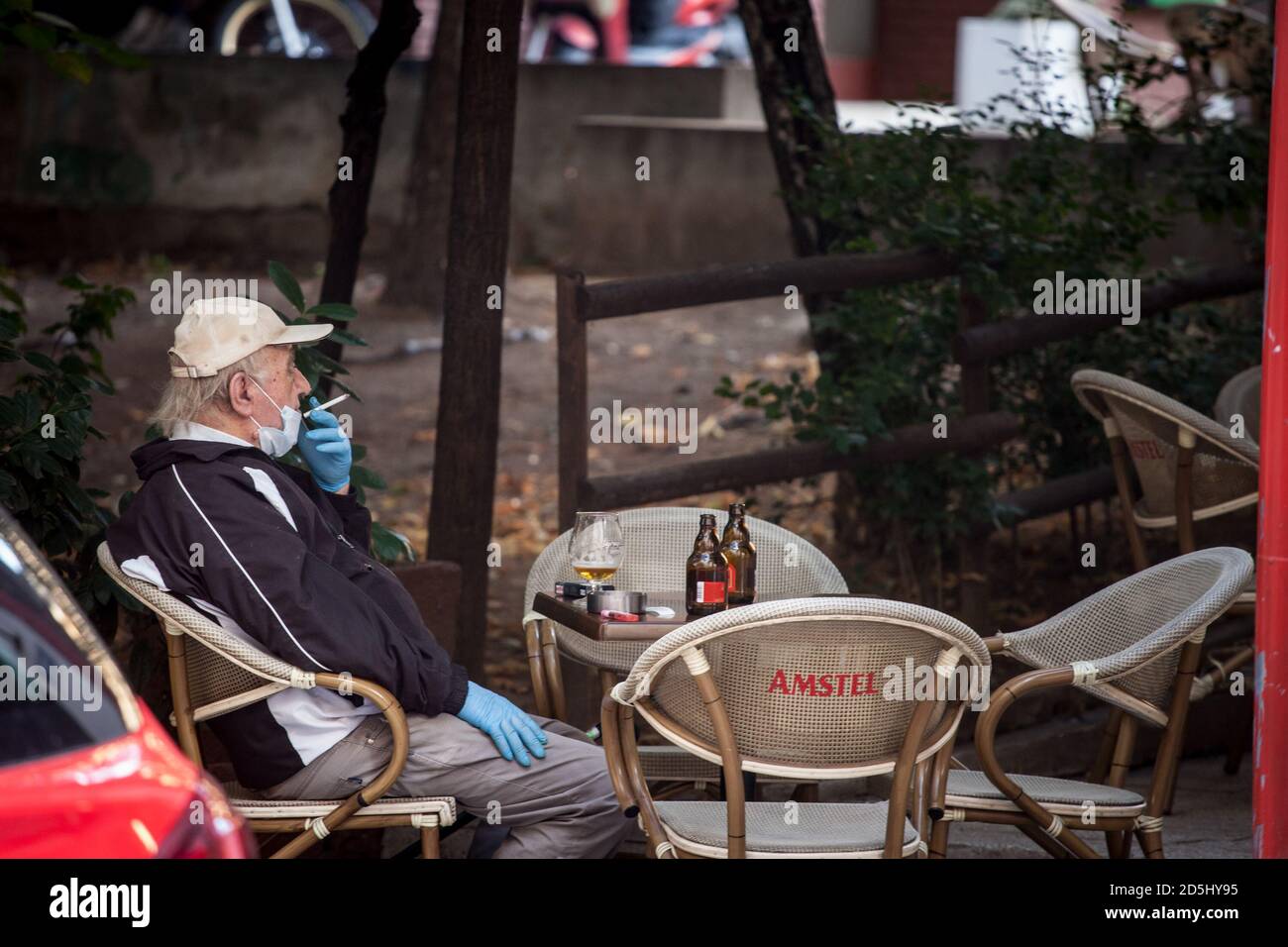 BELGRADE, SERBIE - 4 OCTOBRE 2020 : vieil homme âgé portant un masque respiratoire assis sur la terrasse d'un bar qui boit de la bière et fume de la cigarette Banque D'Images