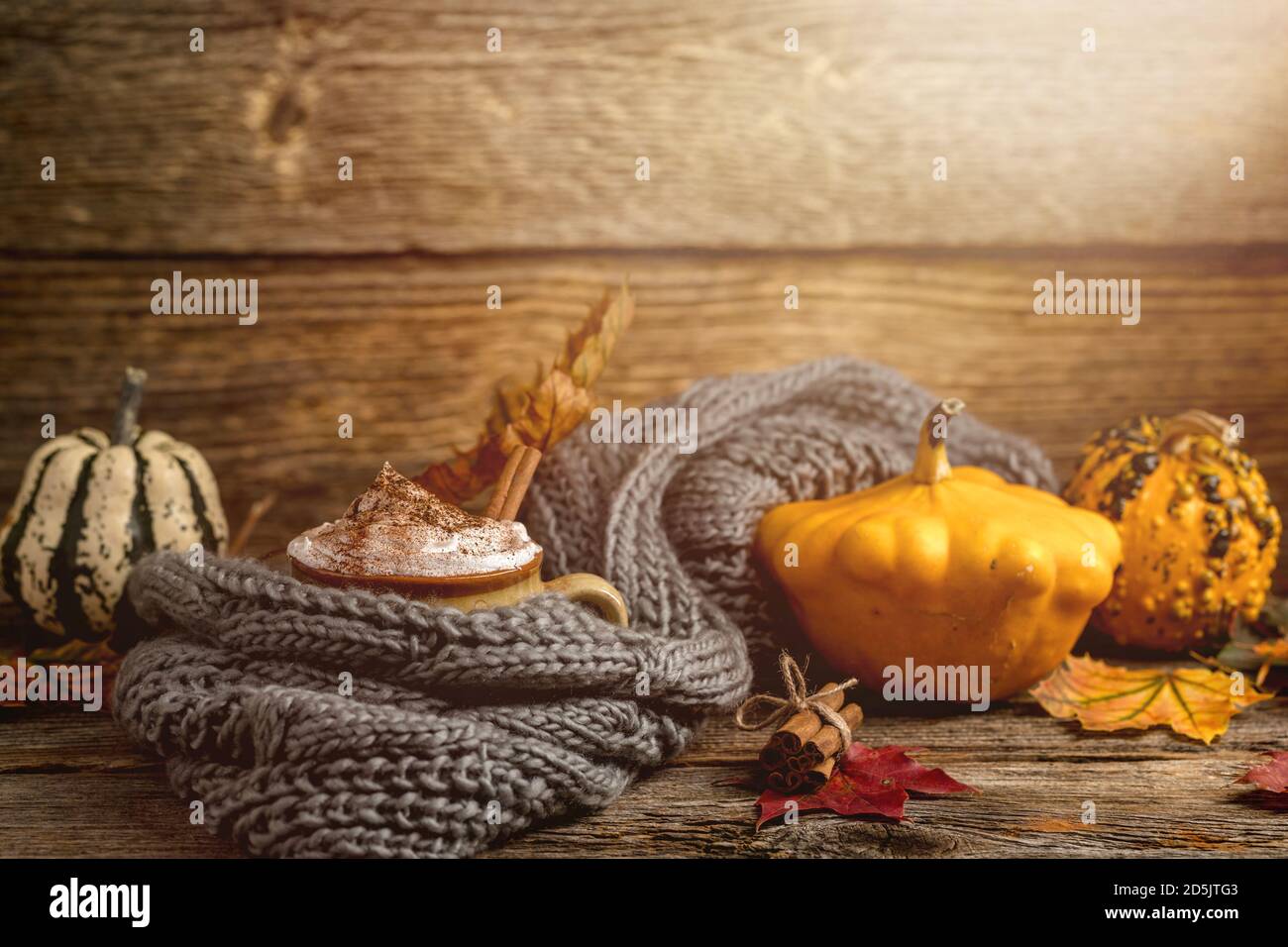 Concept d'automne, encore vie de latte d'épices de citrouille avec crème de lait fouettée et cinamon. Citrouilles colorées et feuilles sèches. Vieux bois naturel à l'arrière Banque D'Images