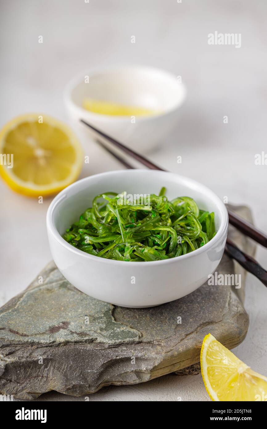 Photo croppée de salade d'algues wakame vertes avec baguette et citron au restaurant Banque D'Images