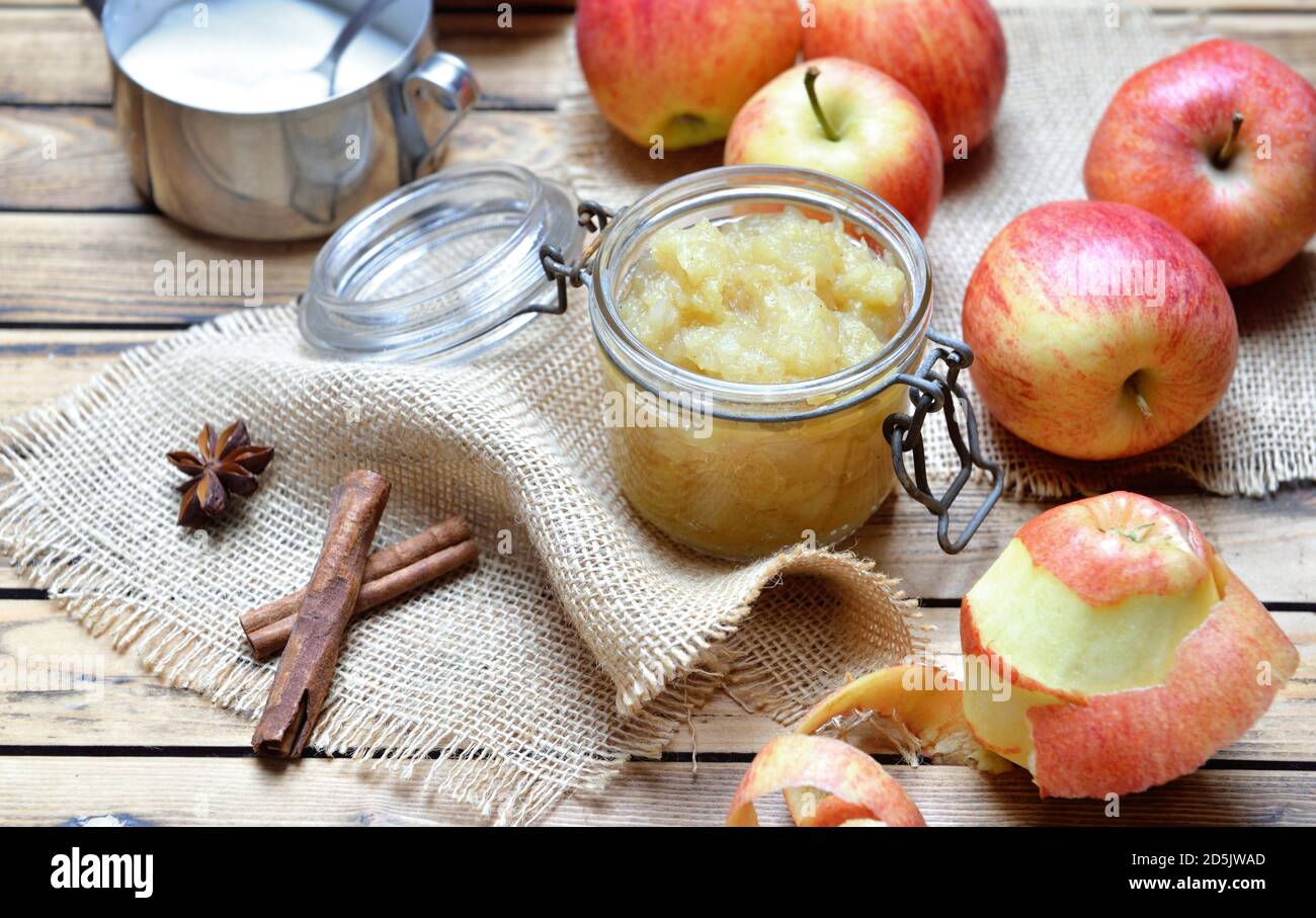 sauce aux pommes maison dans un pot en verre avec des pommes rouges bâton de cannelle sur une table en bois Banque D'Images