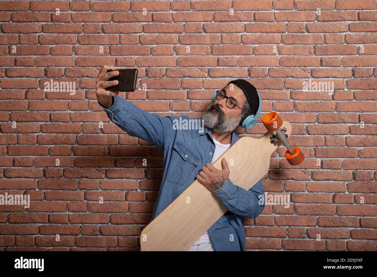 Un boxeur prend un selfie sur son smartphone avec la longue planche sur un fond de mur de briques. Banque D'Images