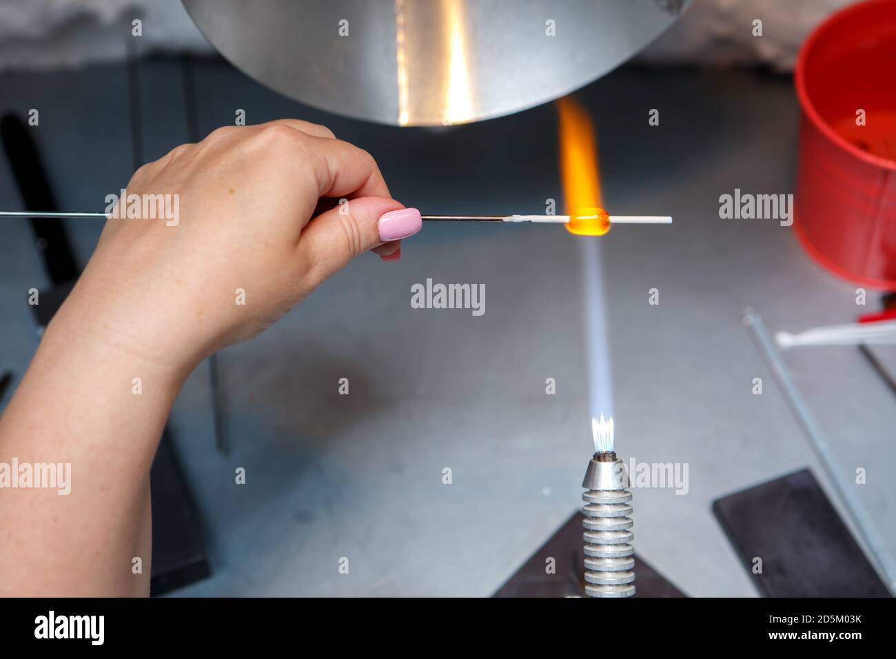 L'artiste chauffe le verre avec un brûleur à gaz. Le processus de fabrication de bijoux en verre. Les mains du maître se rapprochent Banque D'Images