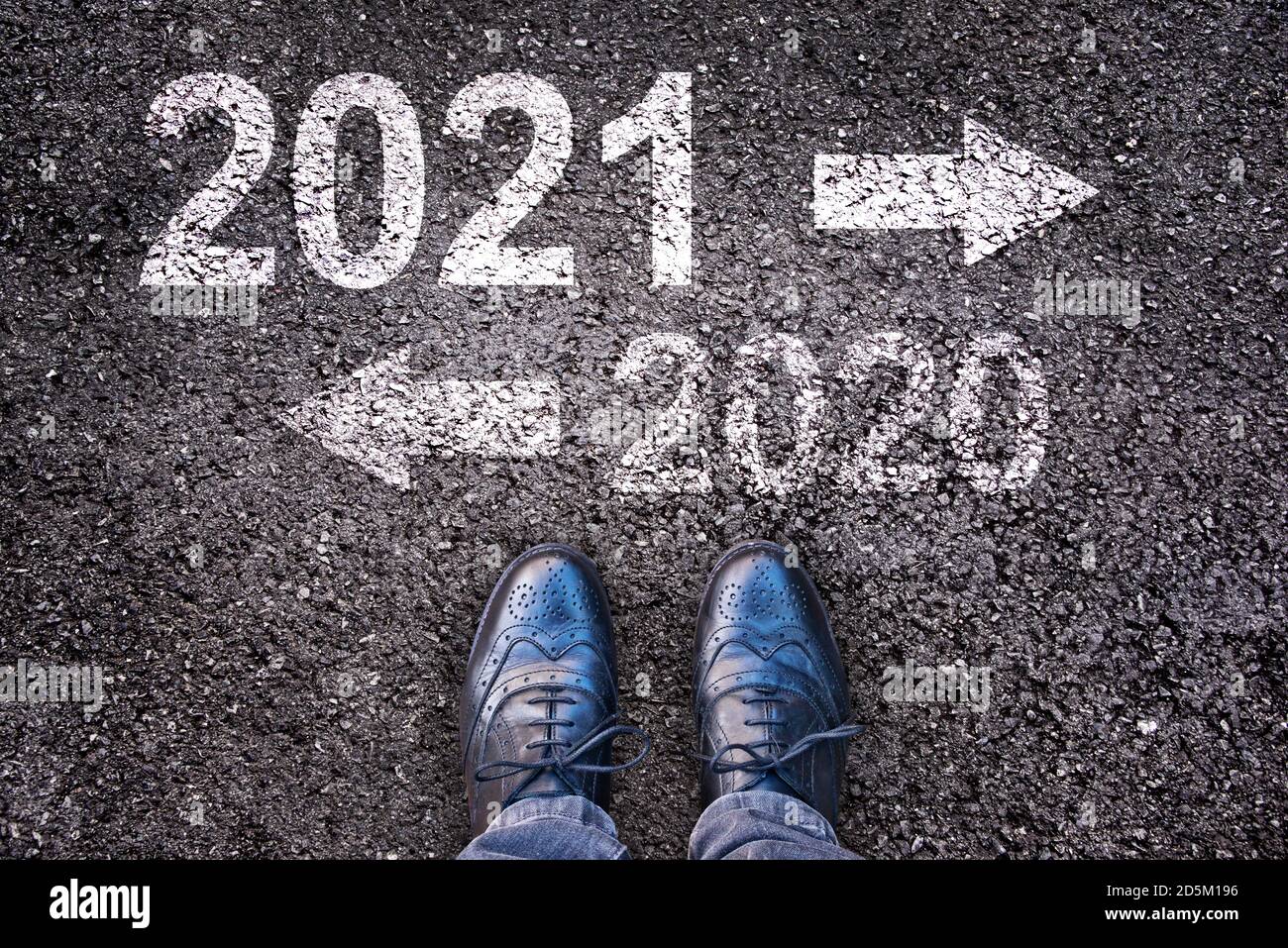 2021 et 2020 avec des flèches de direction écrites sur un asphalte arrière-plan de la route avec jambes Banque D'Images