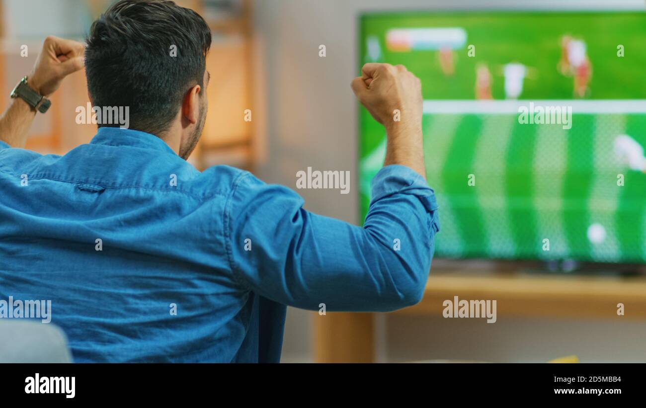 À la maison Sports Fan Watches important match de football à la télévision, applaudisant pour son équipe, célèbre faire le geste OUI après que LE BUT apporte la victoire à son équipe Banque D'Images