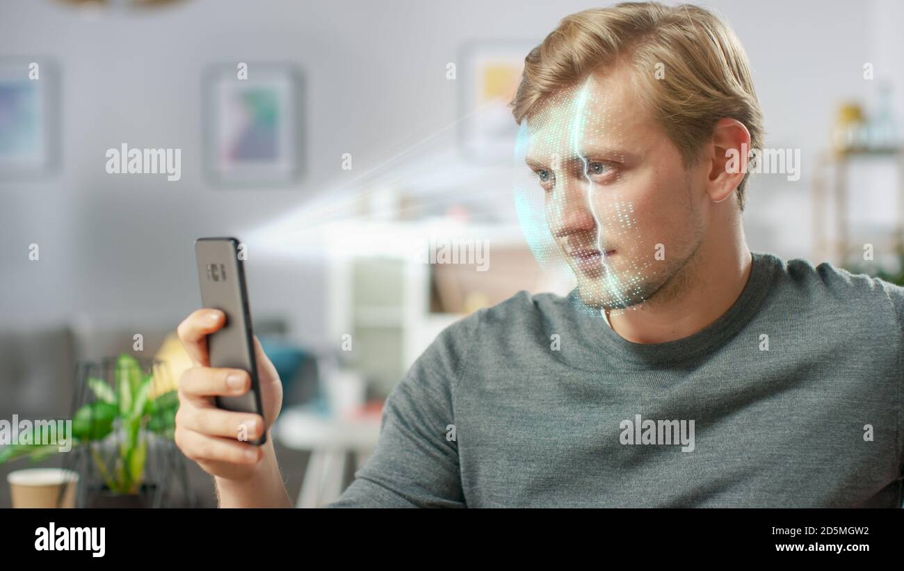 Jeune homme identifié par la reconnaissance faciale biométrique processus de lecture à partir de son smartphone. Concept futuriste : le projecteur identifie l'individu par Banque D'Images