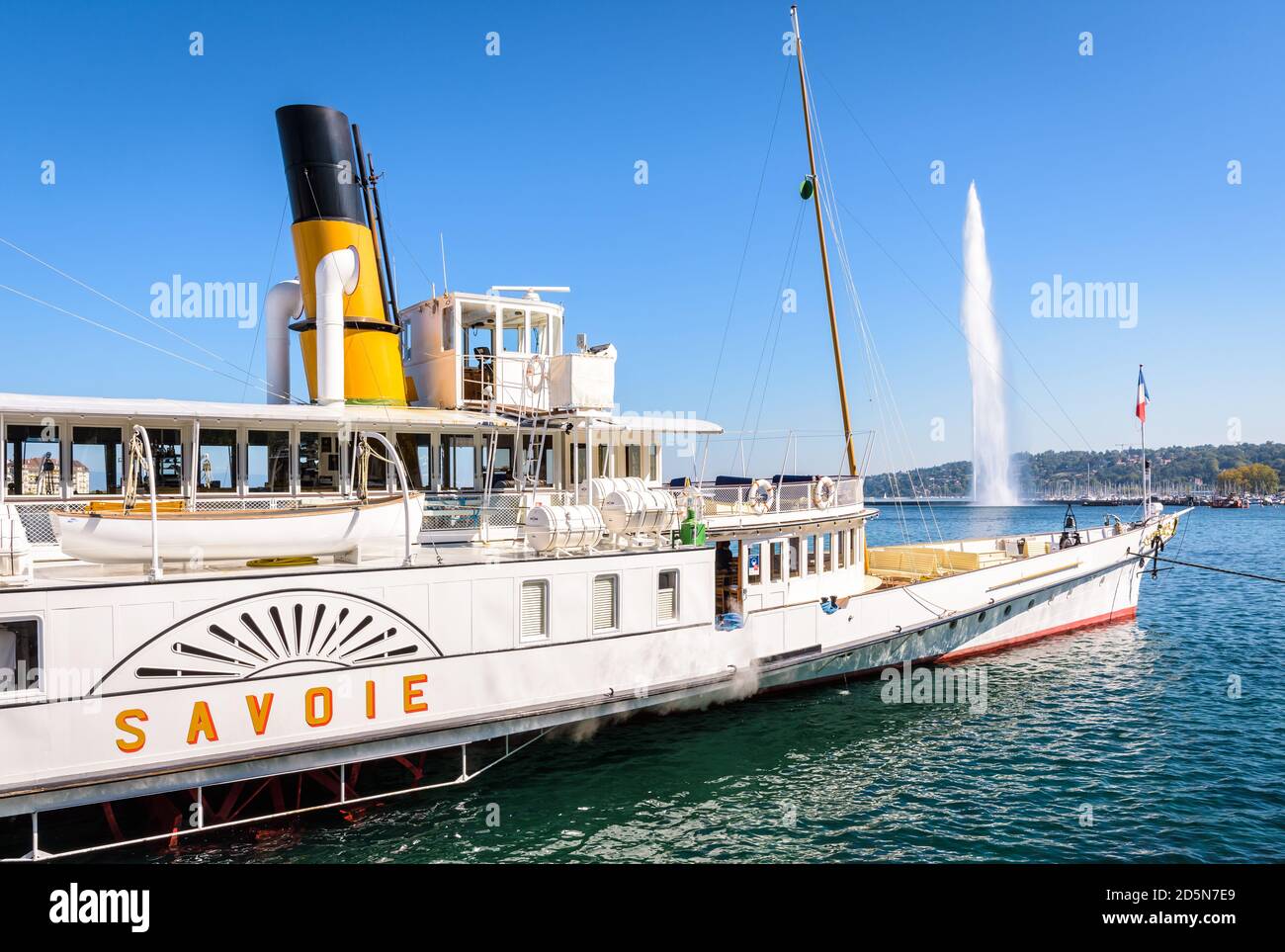 Le bateau à aubes « Lavoie », classé monument historique, est amarré dans la baie de Genève, avec la fontaine jet d'eau Jet d'eau au loin. Banque D'Images
