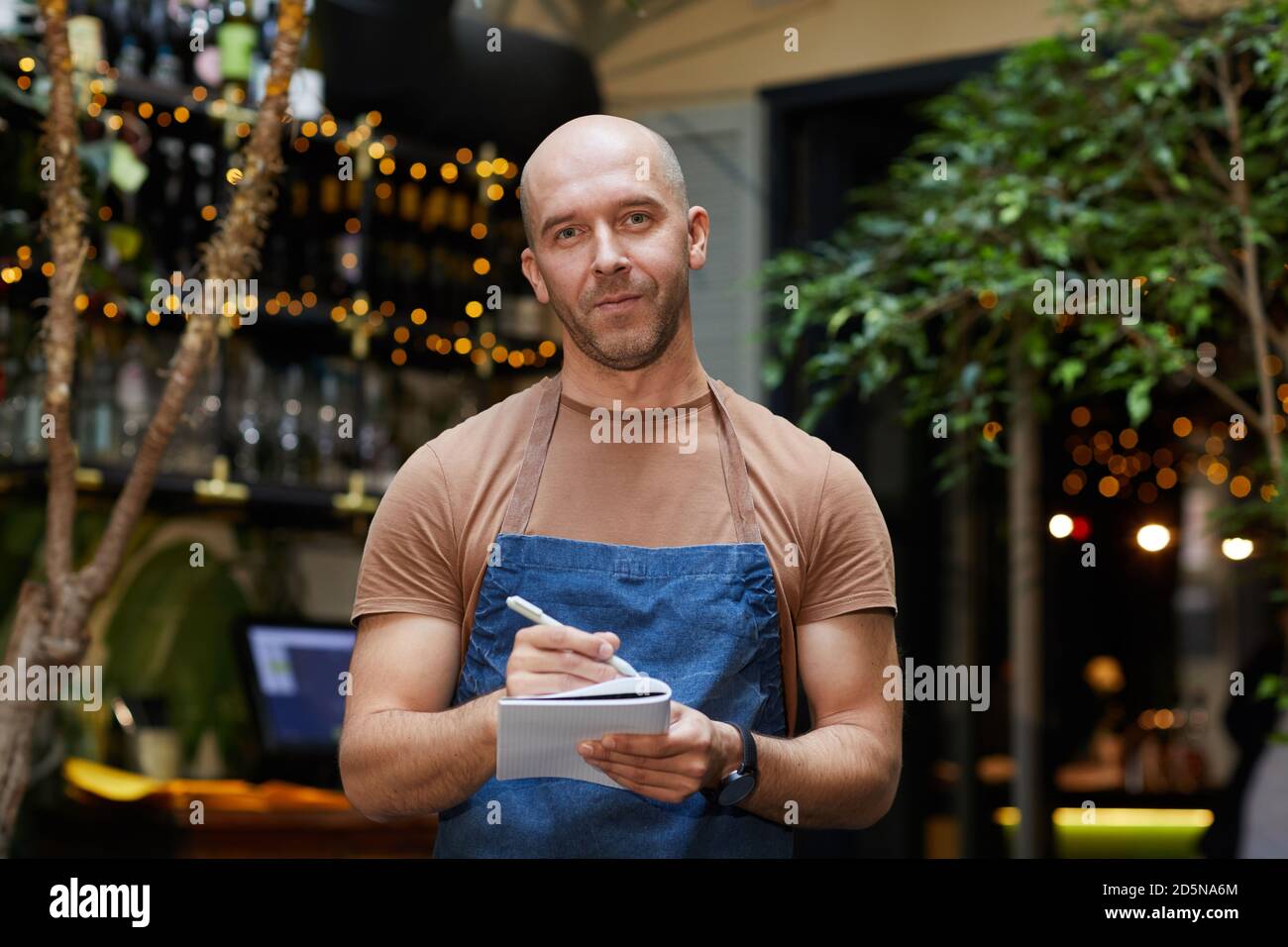 Portrait de serveur mature en uniforme est prêt à prendre l'ordre dans lequel il regarde la caméra au restaurant Banque D'Images