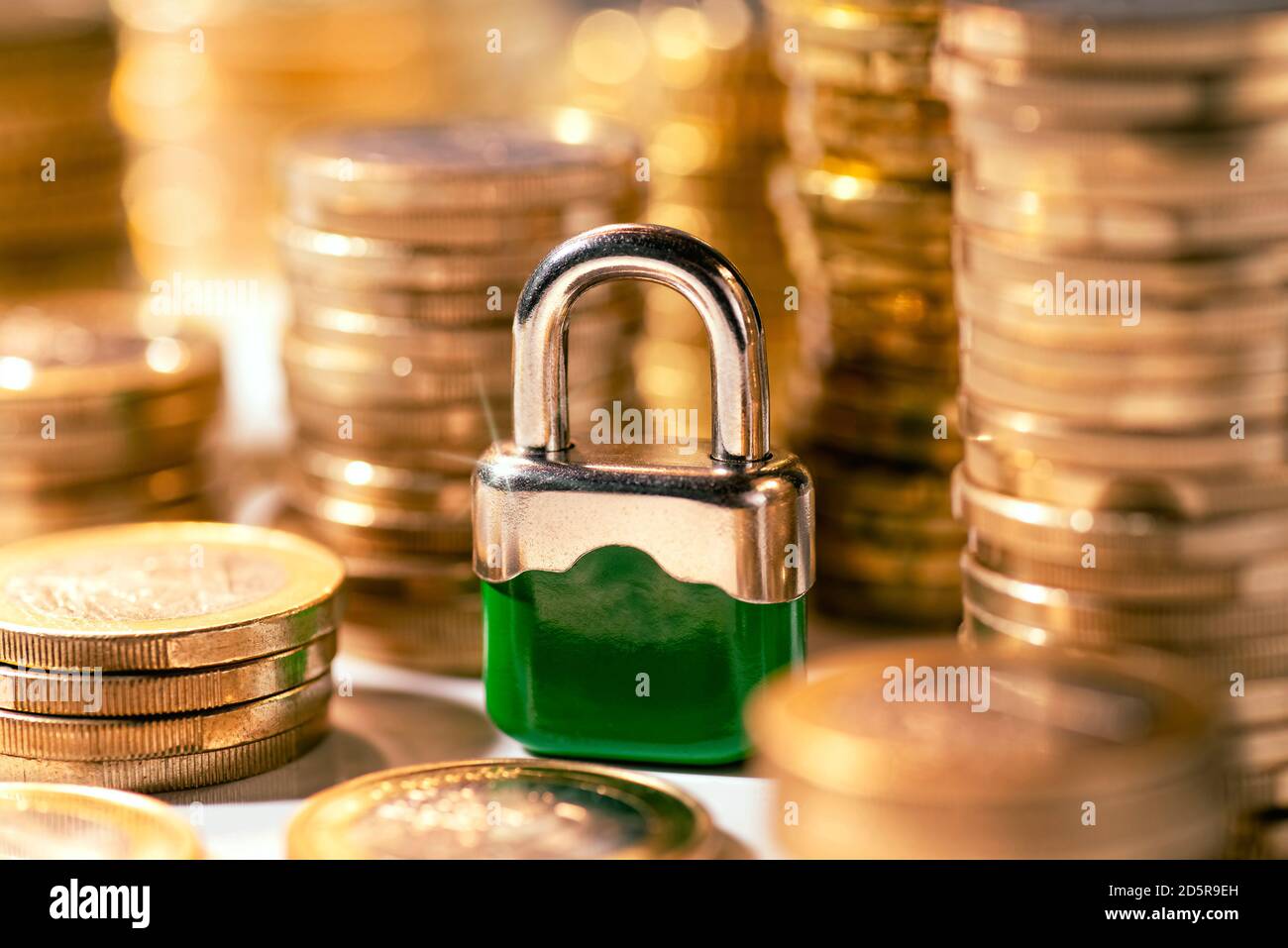 Un petit cadenas se trouve entre les piles de pièces Banque D'Images