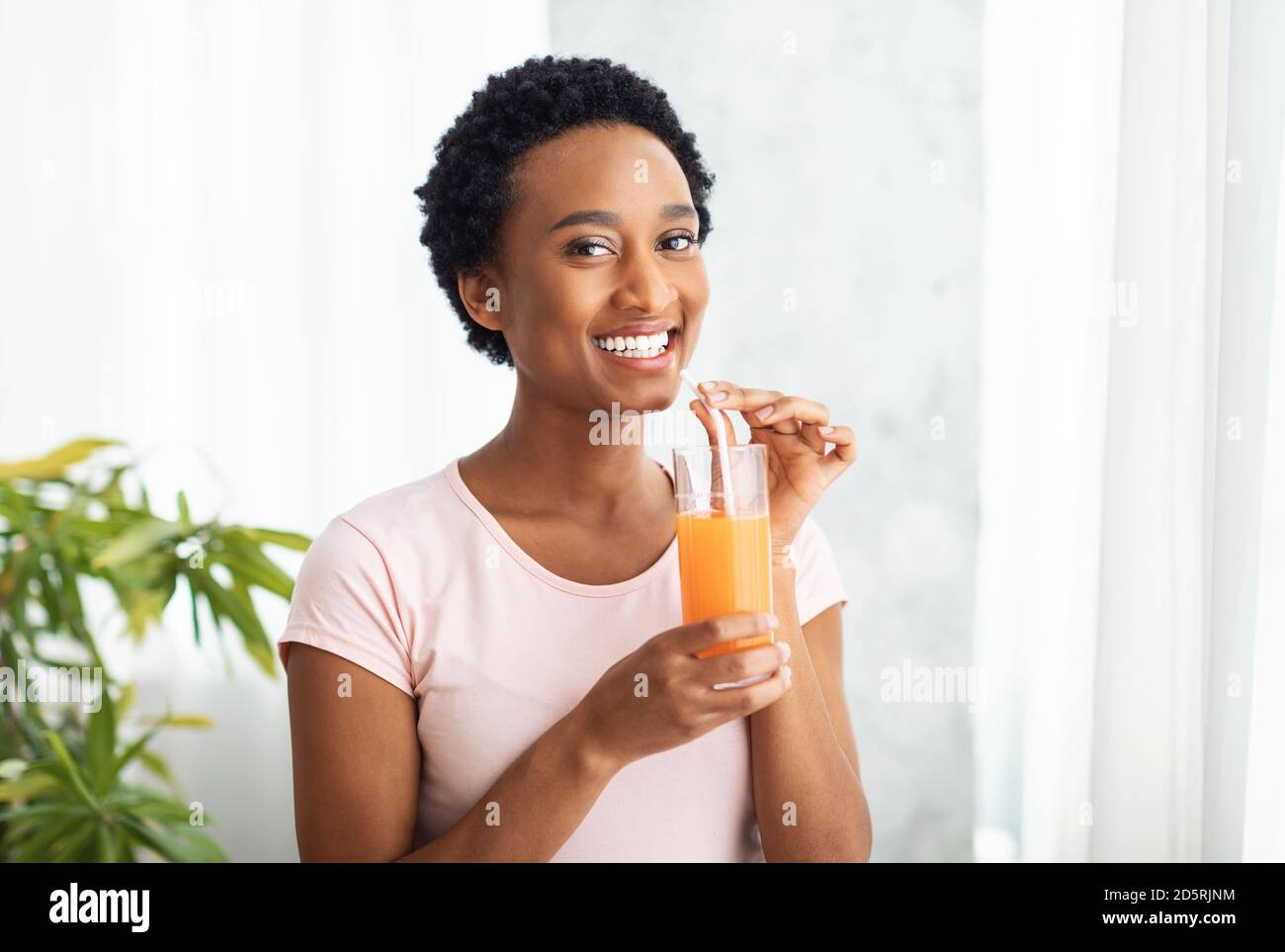 Saine alimentation, régime et désintoxication. Jolie femme afro-américaine qui boit du jus d'orange frais à la maison, espace copie Banque D'Images