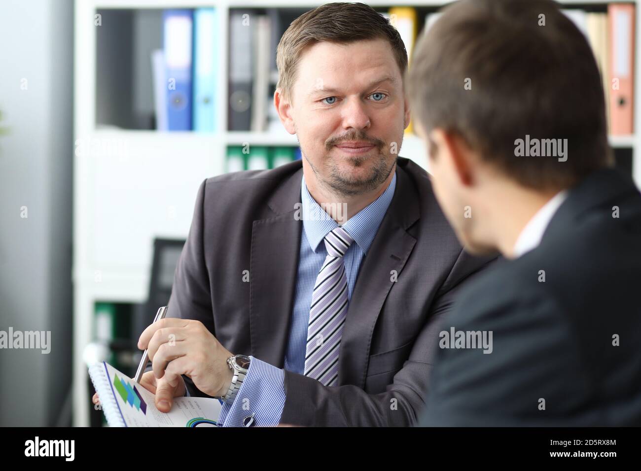 Homme en costume d'affaires montre le graphique avec le stylo sur le document lors d'une réunion avec des clients en portrait de bureau Banque D'Images