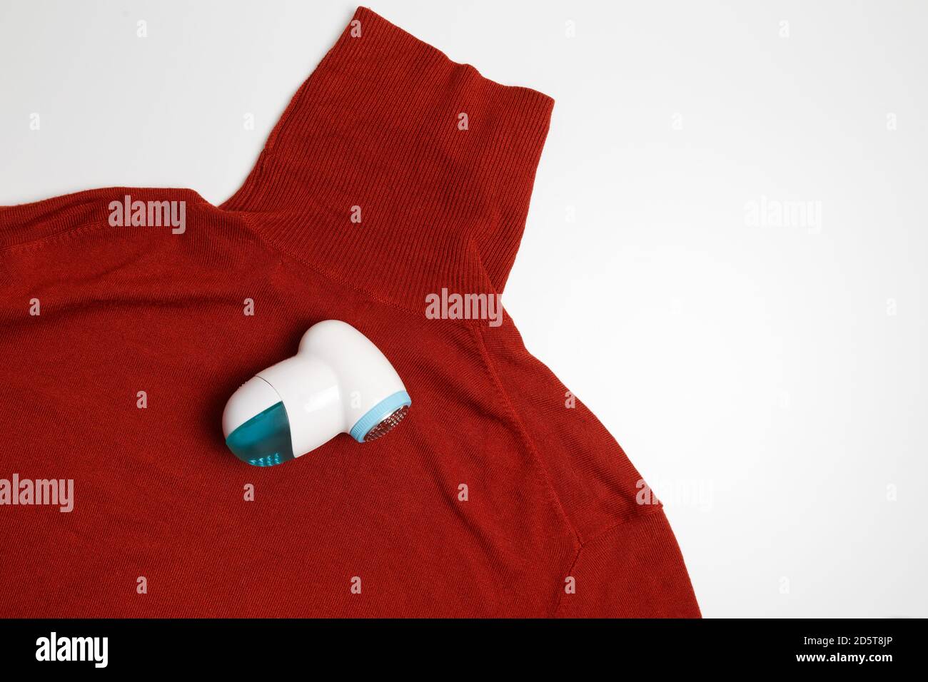 Dispositif d'élimination des peluches des vêtements en laine. Golf avec boule de fuzz isolée sur fond blanc. Banque D'Images