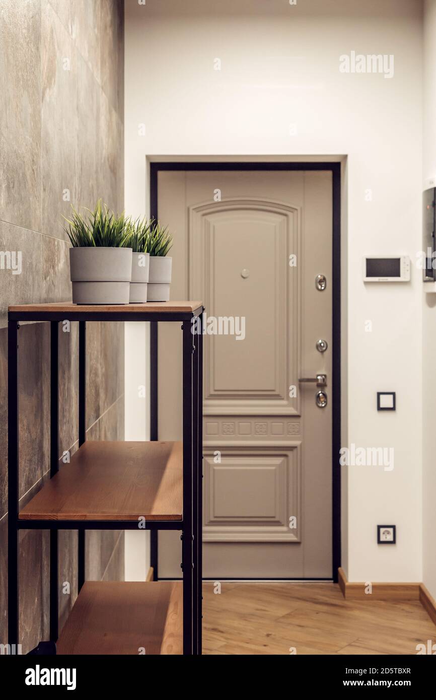 Mur texturé avec carreaux de béton dans le hall. Porte d'entrée, cintre et porte-vêtements dans un style moderne. Banque D'Images