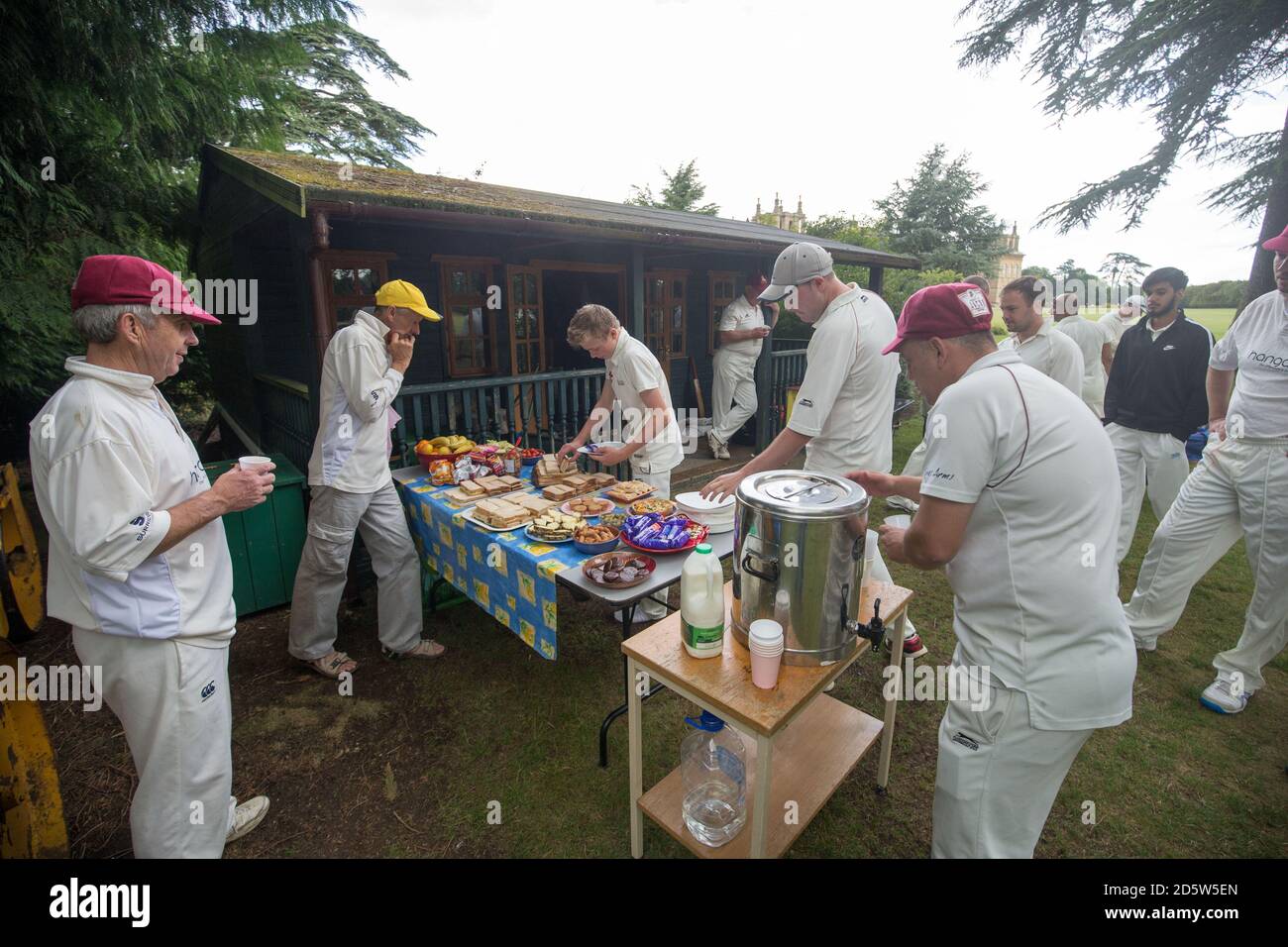 Les joueurs et les officiels s'arrêtent pour le thé en tant que Cricket de Blenheim Park Club jouer un match à domicile contre l'Islip Cricket Club sur La pelouse sud au Palais de Blenheim Banque D'Images