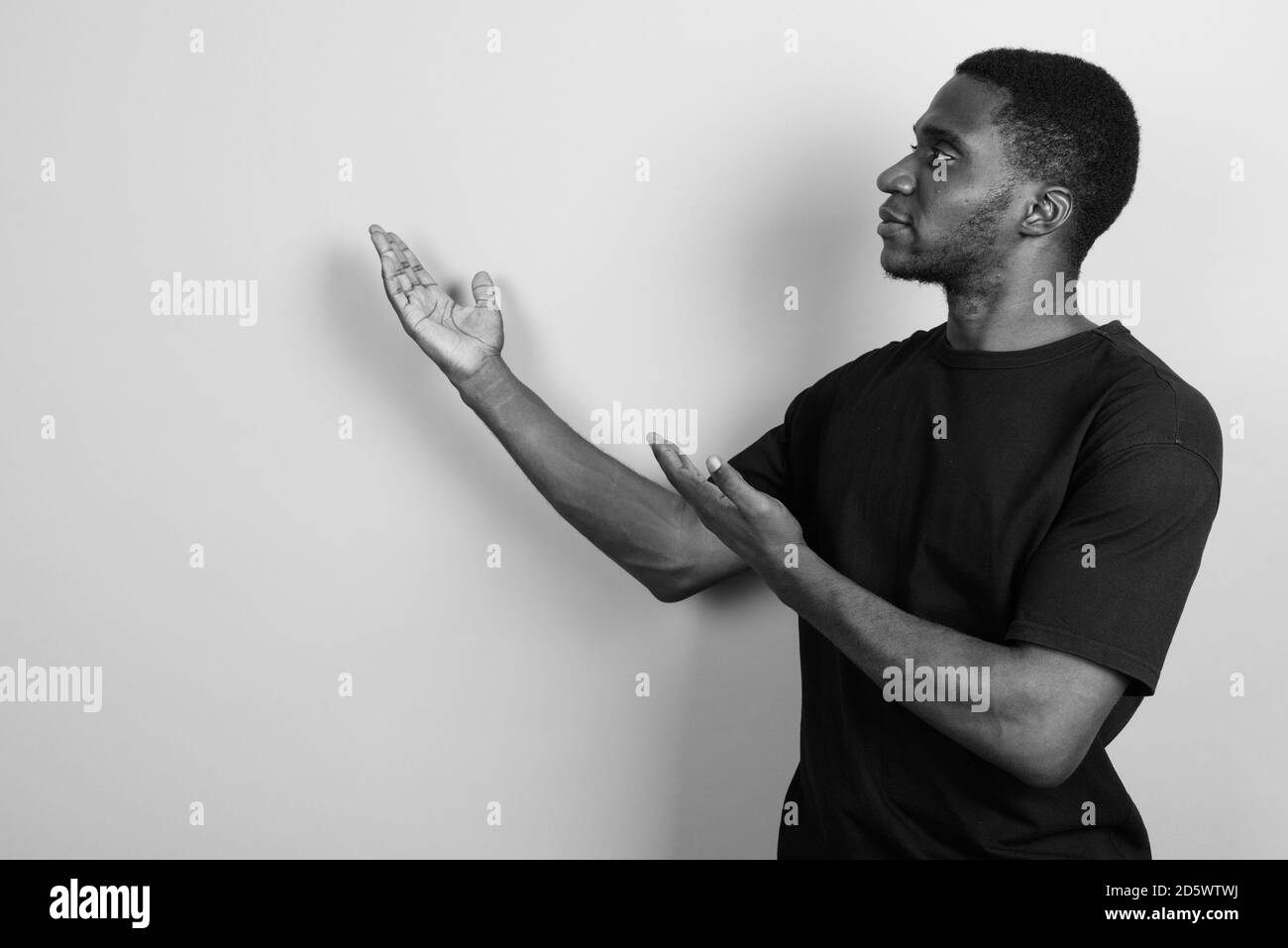 Jeune homme africain portant chemise noire contre l'arrière-plan gris Banque D'Images