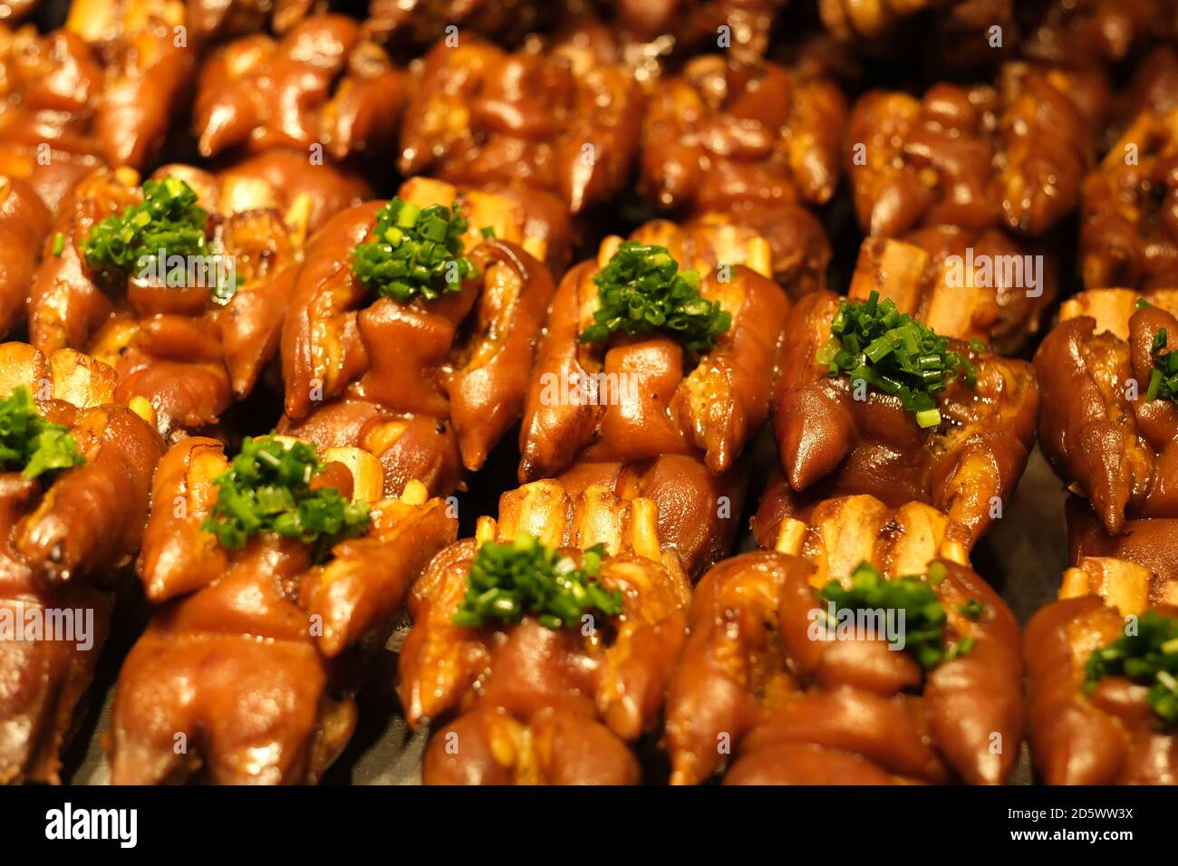 rangées de trotters braisés (pieds de porc) avec échalotes. En-cas chinois traditionnel Banque D'Images