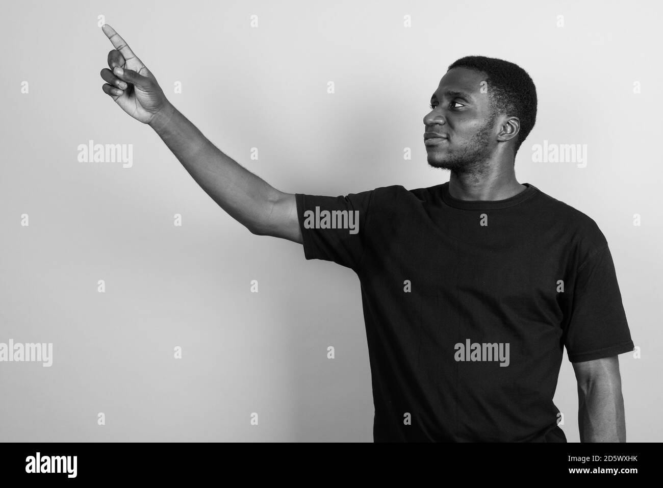 Jeune homme africain portant chemise noire contre l'arrière-plan gris Banque D'Images