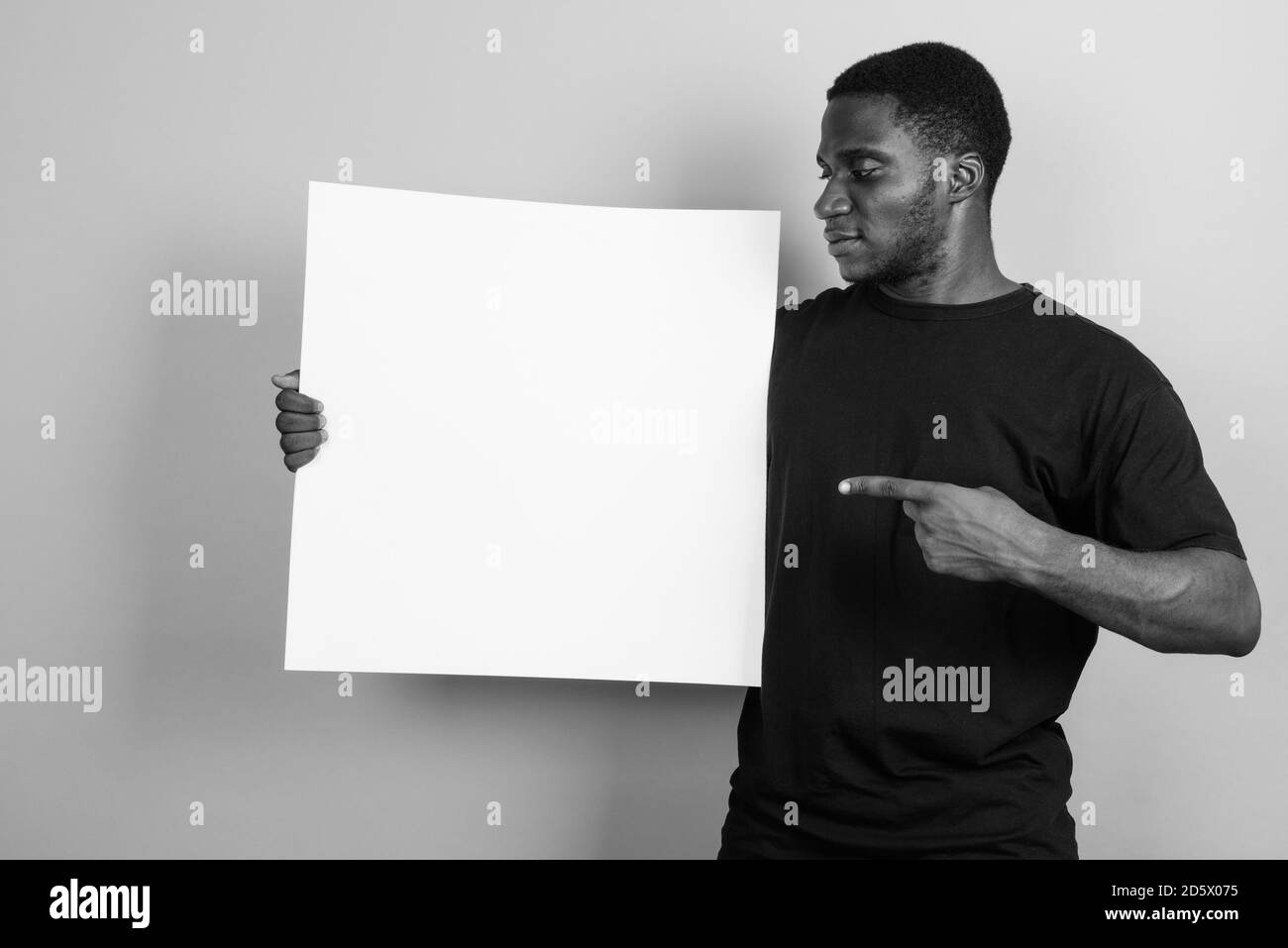 Jeune homme africain portant chemise noire contre l'arrière-plan gris Banque D'Images