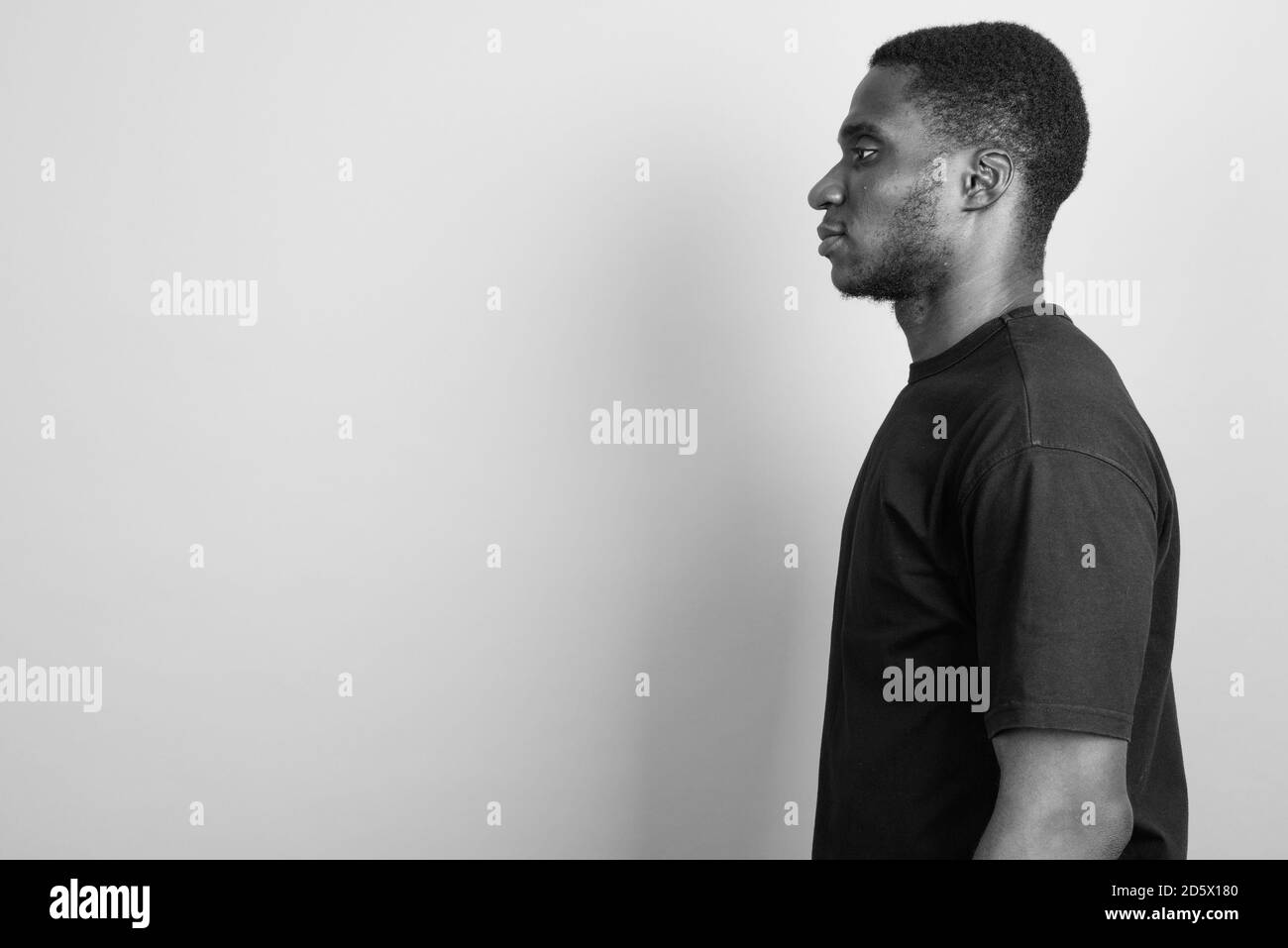 Jeune homme africain portant chemise noire contre l'arrière-plan gris Banque D'Images