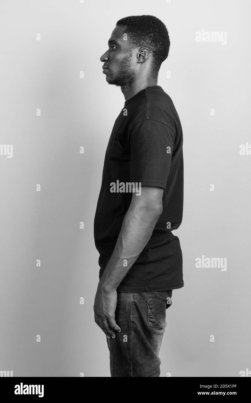 Jeune homme africain portant chemise noire contre l'arrière-plan gris Banque D'Images