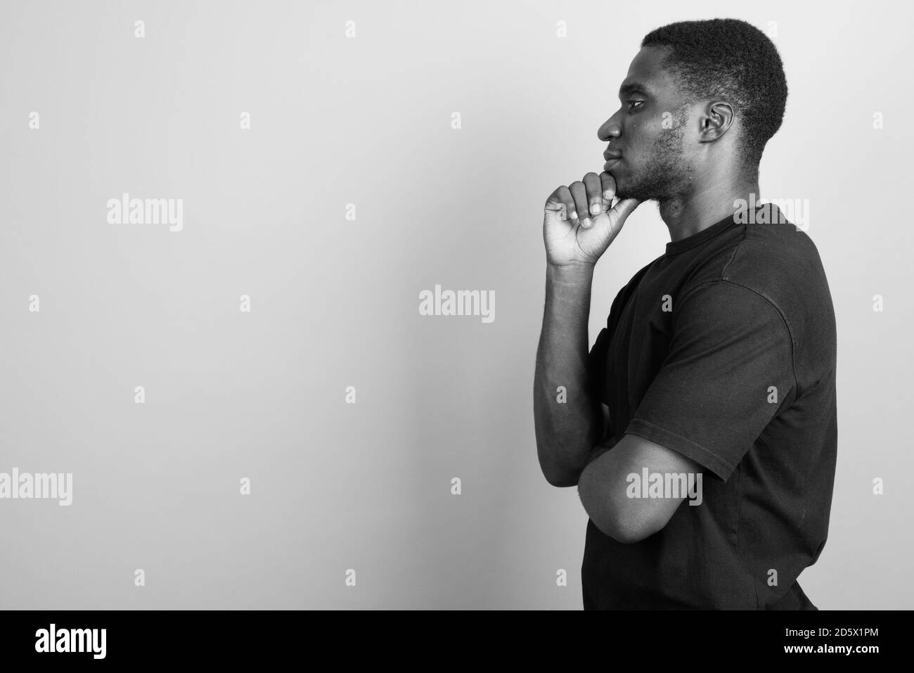 Jeune homme africain portant chemise noire contre l'arrière-plan gris Banque D'Images