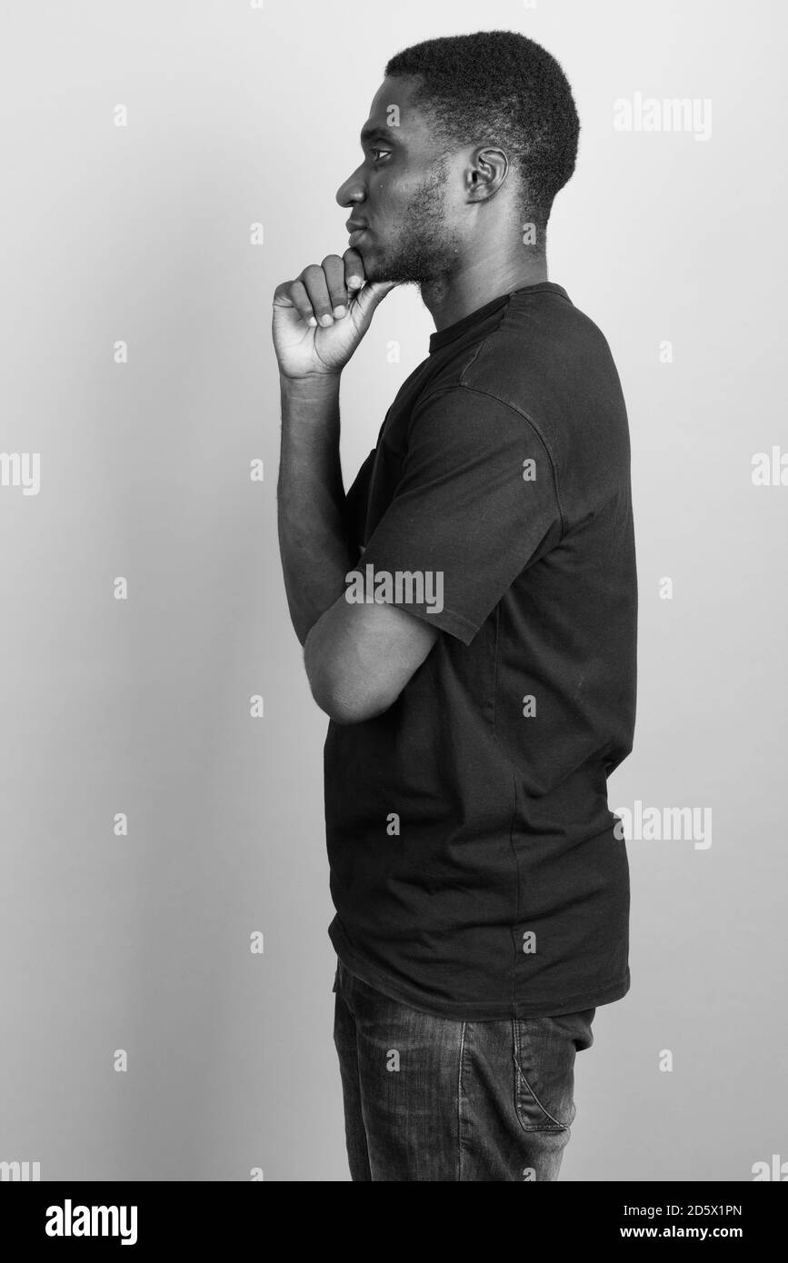 Jeune homme africain portant chemise noire contre l'arrière-plan gris Banque D'Images