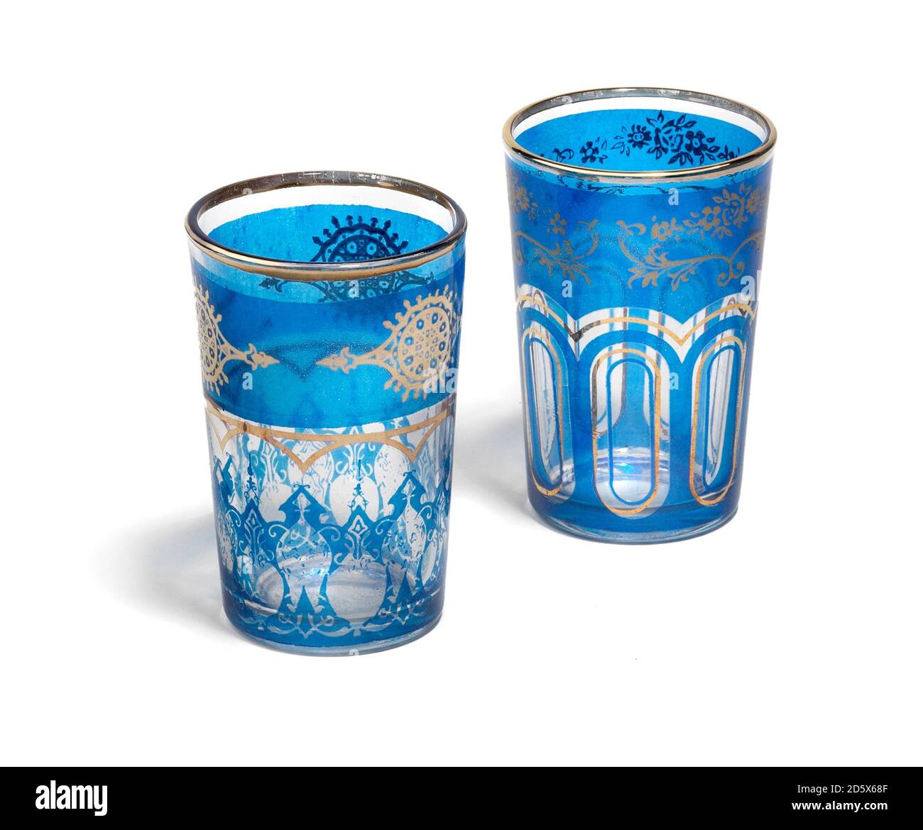 Une paire de verres à thé bleus à bord d'or de style marocain photographiés sur fond blanc Banque D'Images