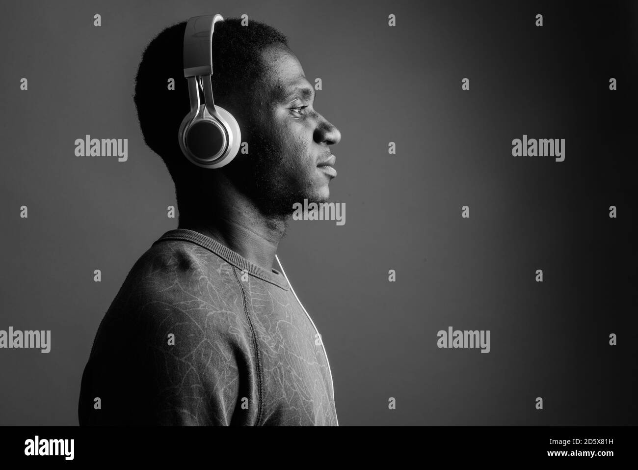 Jeune homme africain d'écouter de la musique à l'arrière-plan gris Banque D'Images