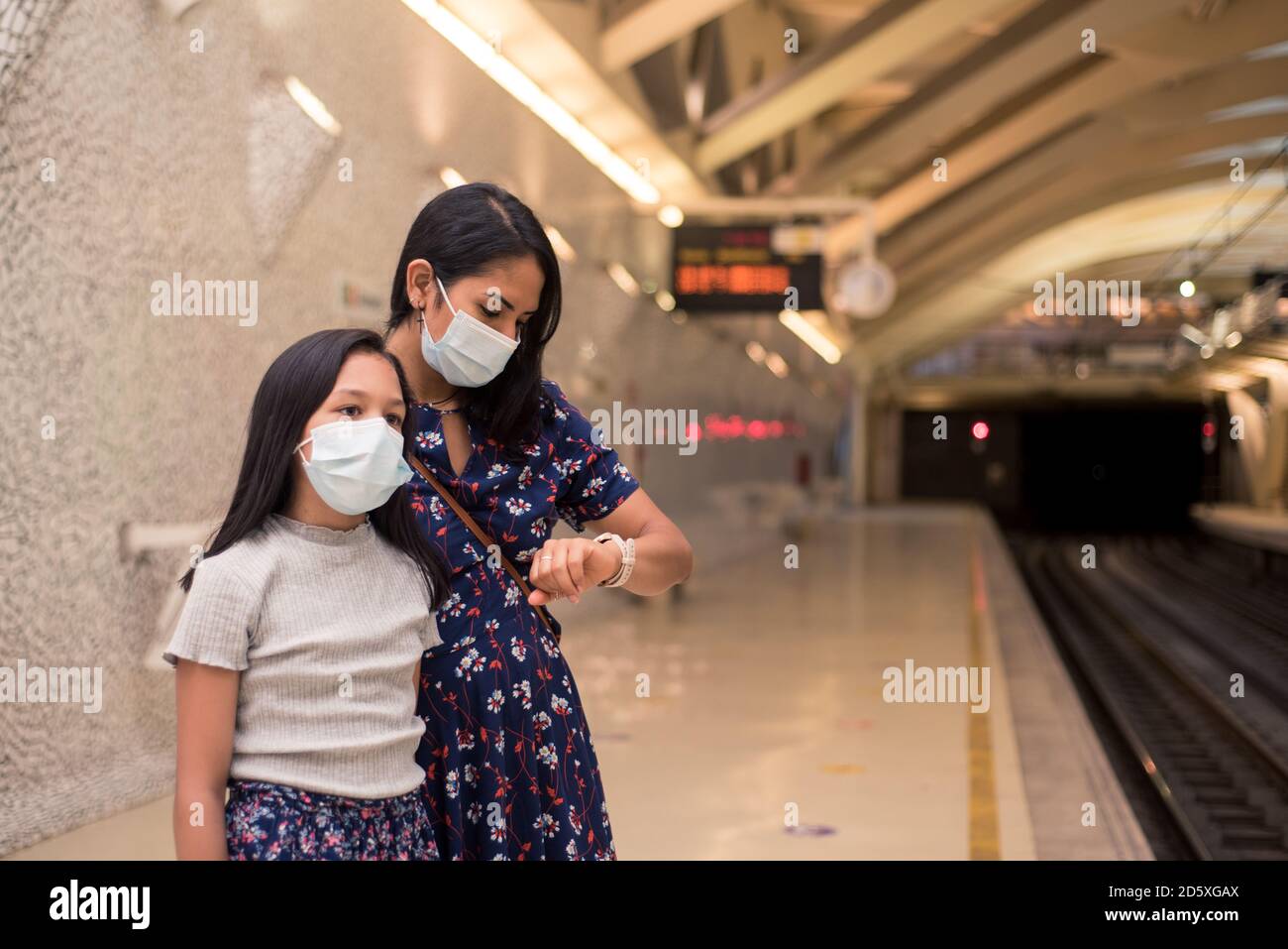 Une jeune femme et sa fille attendent le train. Les filles portant un masque médical sur le poste. Concept de voyage pendant la contagion covid19. Banque D'Images