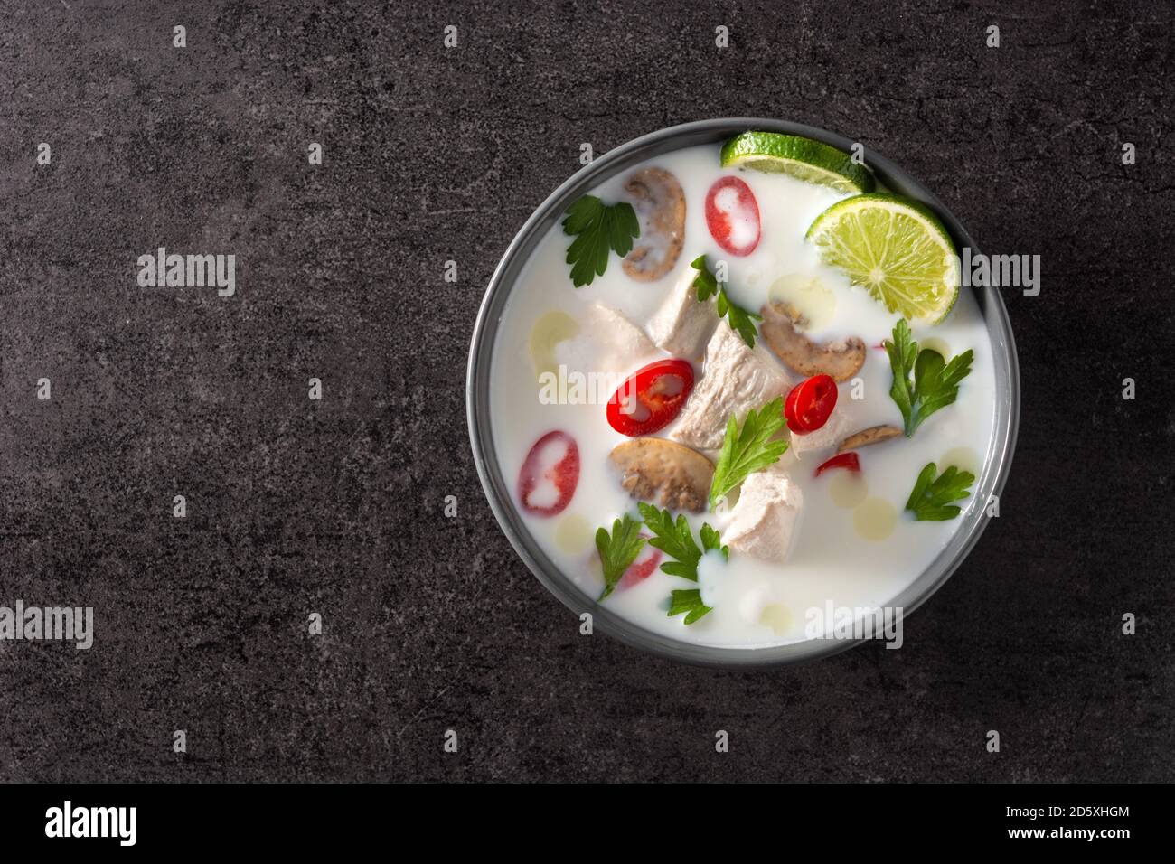Soupe traditionnelle thaïlandaise au lait de coco Tom Kha Gai avec poulet, gingembre, piments, citron vert et champignons sur fond noir Banque D'Images