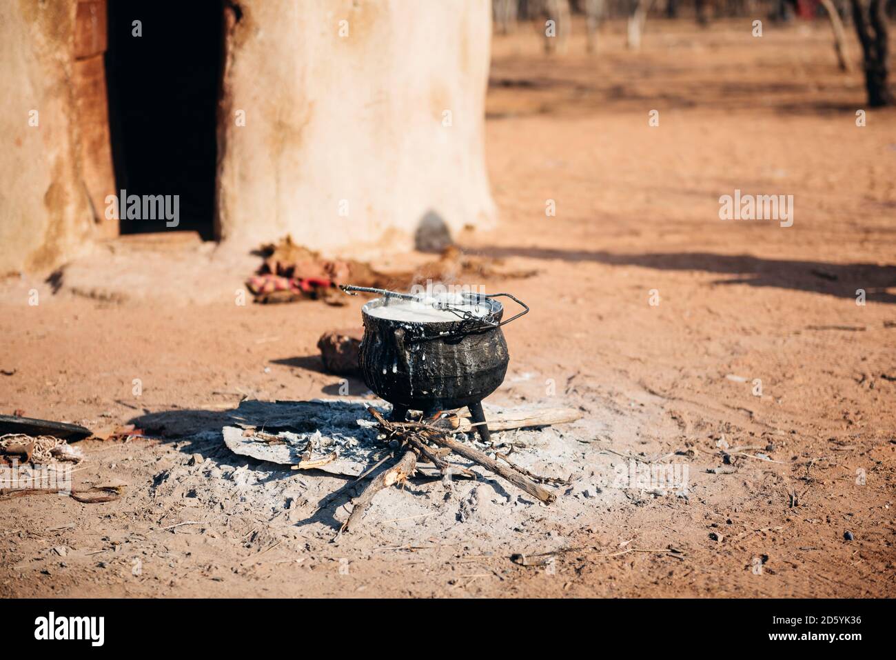 La Namibie, Damaraland, pot de fer l'ébullition sur un petit feu devant une cabane dans un village Himba Banque D'Images