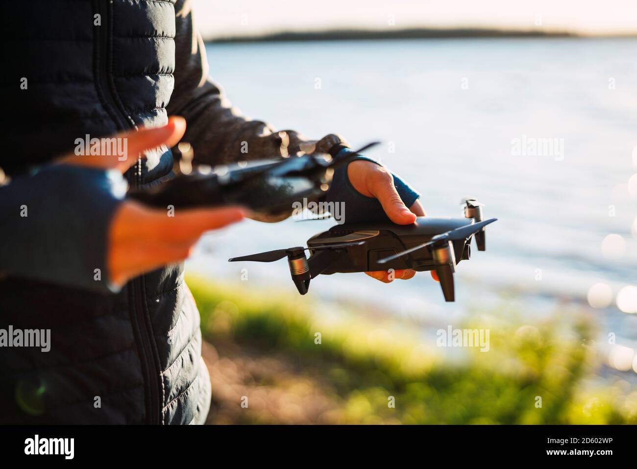 Homme tenant un drone et un télétéléphonique à un lac Banque D'Images