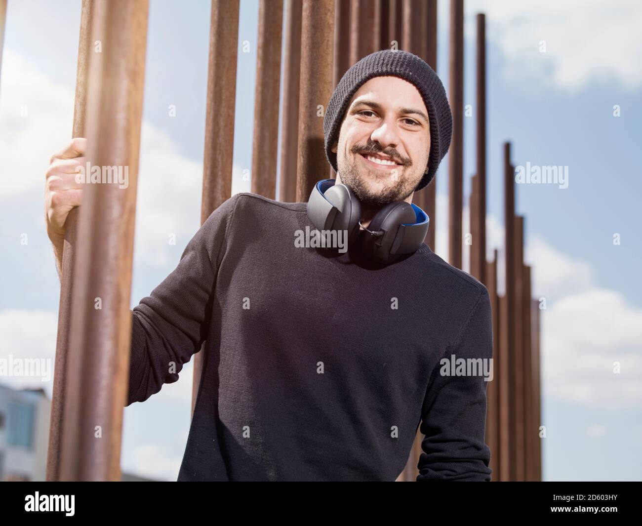 Portrait of smiling young man with headphones portant chapeau de laine et pull noir Banque D'Images