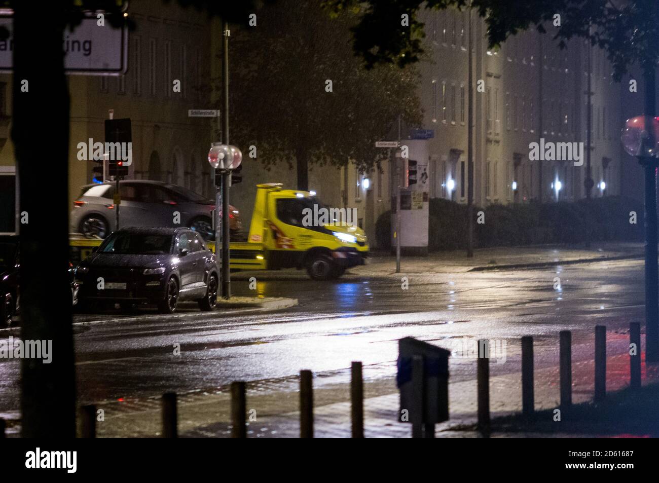 Pluie la nuit de circulation. Camion de remorquage transportant une voiture électrique. Banque D'Images